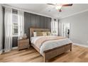 Relaxing main bedroom featuring a wood accent wall, and large windows with natural light and wood floors at 4465 Tubular Run, Land O Lakes, FL 34638