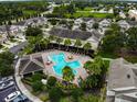 Aerial view of the community pool with lounge chairs, lush landscaping, and nearby parking at 10132 Post Harvest Dr, Riverview, FL 33578