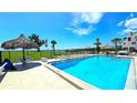 Community swimming pool with clear blue water, tiki hut, and lounge chairs for relaxing by the poolside at 13 Windrush Bay Dr, Tarpon Springs, FL 34689