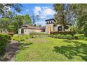 Inviting home featuring unique tower, arched windows, and well-manicured landscaping at 13503 Gopher Pond Ct, Hudson, FL 34669