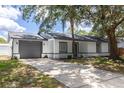 Home's facade showcasing a gray garage door, concrete driveway, fresh paint and manicured landscaping at 22716 Penny Loop, Land O Lakes, FL 34639