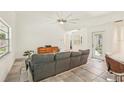 Living room with a gray sofa, tiled floor, ceiling fan and glass door out to the backyard at 2896 Grand Cayman St, Sarasota, FL 34231