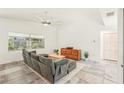 Living room with a gray sofa, wood dresser, ceiling fan and large window that looks out to the yard at 2896 Grand Cayman St, Sarasota, FL 34231