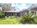 Exterior view of a home with screened-in back porch and lush tropical landscaping around the property at 5540 Cyril Dr, Dade City, FL 33523