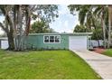 Charming single-story home with attached garage, green exterior, and well manicured lawn at 607 E River Dr, Temple Terrace, FL 33617