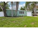 Charming home with an attached garage, green exterior, manicured lawn, and mature shade trees at 607 E River Dr, Temple Terrace, FL 33617