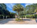 Elegant gated entrance features a central palm tree surrounded by lush greenery and beautiful landscaping at 824 Lantern Way, Clearwater, FL 33765