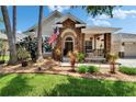 Stunning front exterior showcasing the home's stone accents, front porch, landscaping, and American flag at 8704 Winsome Way, Land O Lakes, FL 34637