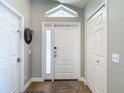 Inviting foyer with white door, sidelight, transom window, and wood-look flooring at 8717 Persea Ct, Trinity, FL 34655