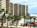 Stunning exterior view of a beachfront condo building with pool, palm trees, and ocean views at 880 Mandalay Ave # N311, Clearwater Beach, FL 33767