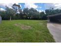 Large grassy backyard with scattered trees and partial fence on sunny day at 9910 Jerome Dr, New Port Richey, FL 34654