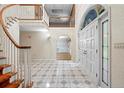 Grand foyer with a winding staircase, tiled floors, and a decorative peacock-themed window above the entrance at 11159 Cindy Dr, Brooksville, FL 34601
