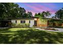 Charming single story home at sunset featuring a well maintained lawn and covered carport at 1402 E Mimosa Dr, Plant City, FL 33563