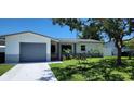 Inviting single-story home featuring a manicured lawn, mature landscaping, and a single car garage at 1583 Eunice Ln, Clearwater, FL 33756