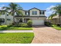 Charming two-story home showcasing lush landscaping, a brick driveway, and a welcoming facade at 19209 Long Lake Ranch Blvd, Lutz, FL 33558