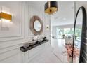 The foyer has white walls with marble floors, a round mirror, and a black console table with decor at 32203 Mahogany Valley Dr, Wesley Chapel, FL 33543