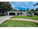 Beautiful single-story home featuring a well-maintained lawn and a dark garage door at 3411 Glossy Ibis Ct, Palm Harbor, FL 34683