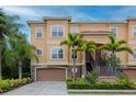 Beautiful townhome showcasing a two-car garage and meticulous landscaping with mature palm trees at 6513 Sand Shore Ln, New Port Richey, FL 34652