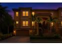 Inviting townhouse featuring warm exterior lighting, two-car garage and lush landscaping at twilight at 6513 Sand Shore Ln, New Port Richey, FL 34652