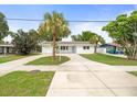 Inviting single-Gathering home with a long driveway, lush landscaping, and a freshly painted white exterior at 7571 Ridge Rd, Seminole, FL 33772