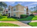 Two-story condo building with screened balconies, well-kept landscaping, and green grass at 9481 Highland Oak Dr # 806, Tampa, FL 33647