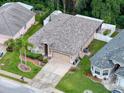 Aerial view of the property showcasing a well-maintained home with a manicured lawn, mature trees, and a two-car garage at 12200 Hunters Lake Dr, New Port Richey, FL 34654