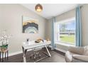 Bright office features a modern white desk, decorative light fixture and large window with serene outdoor views at 12333 Harris Hawk Rd, Weeki Wachee, FL 34614