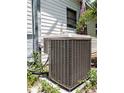 A gray air conditioning unit sits on a concrete base, surrounded by shrubbery and green plants at 12704 Lacey, New Port Richey, FL 34654