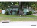 This house has a lush front yard with grass, mature trees, and bushes adding to its curb appeal at 2058 Dodge St, Clearwater, FL 33760