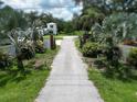 Charming driveway framed by lush greenery and palm trees, leading to the beautiful home in the background at 21921 Us Highway 98, Dade City, FL 33523