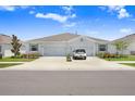 A modern duplex showcasing a well-kept front yard and a clean driveway with car parked in front of the garage at 31426 Ancient Sage Rd, Wesley Chapel, FL 33545