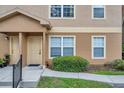 Inviting tan condo exterior featuring a quaint, covered entryway and well-manicured landscaping at 36243 Lake Chase Blvd # 102, Zephyrhills, FL 33541