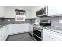 Modern kitchen featuring stainless steel appliances, white cabinetry, gray backsplash, and granite countertops at 3628 Holiday Lake Dr, Holiday, FL 34691
