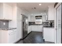 Well-lit modern kitchen with stainless steel appliances, granite countertops, white cabinets, and dark tile flooring at 3628 Holiday Lake Dr, Holiday, FL 34691
