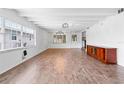 Open-concept living room with wood floors, white walls and ceiling beams, updated lighting, and large windows at 3909 W Lemon St, Tampa, FL 33609