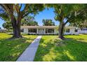 Attractive single-story home with well-kept lawn, mature trees, and stone walkway to the front door at 4391 Ne Cherry Ne St, St Petersburg, FL 33703