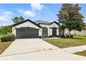 Charming one-story home boasts a well-manicured lawn, two-car garage, and classic stucco exterior with black trim at 5390 Greystone Dr, Spring Hill, FL 34609