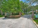 Community entrance featuring an ornate gate, brick pillars, and meticulously maintained landscaping, offering secure access at 8711 Crescent Forest Blvd, New Port Richey, FL 34654
