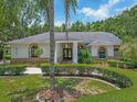 Charming home featuring a manicured front yard with lush landscaping and a welcoming entrance with stately columns at 8711 Crescent Forest Blvd, New Port Richey, FL 34654