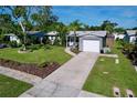 Single story home featuring a long driveway, a well maintained lawn, mature trees, and an attached one-car garage at 8848 56Th N Way, Pinellas Park, FL 33782