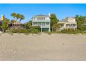 Stunning two-story house with white balconies, perfectly positioned on the sandy beach at 20060 Gulf Blvd, Indian Shores, FL 33785