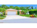 Exterior of a peach-colored home with a white garage door, palm trees, and colorful landscaping at 11116 118Th St, Seminole, FL 33778