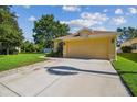 Yellow home with a two-car garage and landscaped front yard, under a sunny sky at 11125 Shelter Cove Loop, New Port Richey, FL 34654