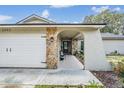 Home exterior featuring stone accents, arched entryway, and well-maintained landscaping at 1403 Tallahassee Dr, Tarpon Springs, FL 34689
