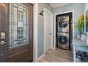 Hallway with decorative door, stacked washer and dryer, and wood-look tile flooring at 1403 Tallahassee Dr, Tarpon Springs, FL 34689