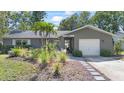 Charming single-story home featuring lush landscaping, a garage, and inviting front entry at 2850 Doone Cir, Palm Harbor, FL 34684