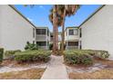 Condominium exterior showcasing stucco walls, screened balconies, green shrubs, and a walkway on a sunny day at 4611 W North B St # 228, Tampa, FL 33609