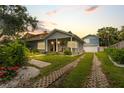 Charming home with lush front yard, a quaint porch, and an inviting driveway with manicured grass at 58 Aster St, Clearwater Beach, FL 33767