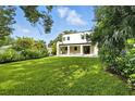 Expansive backyard featuring lush green grass, mature trees, and a covered patio of a modern home at 5816 S 3Rd St, Tampa, FL 33611