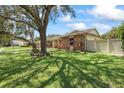 Well-maintained home showcasing a spacious lawn, brick exterior, and a privacy fence at 6706 Dunes Ln, Temple Terrace, FL 33617